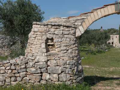 A introdurre la struttura c�� un arco in tufo sostenuto da due pilastrini in pietra calcarea. In uno di essi notiamo un volto con le sembianze di un anziano con il cappello, realizzato a rilievo all�interno di una piccola nicchia